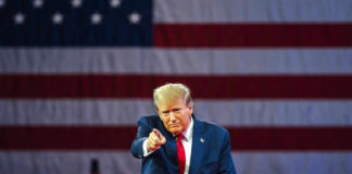 Man points in front of American flag backdrop.