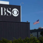 Attack Raises Hate Crime Questions CBS sign on building, American flag in background.