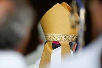 2126614781 Bishop wearing a golden mitre during a ceremony