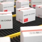 China’s Tech Titans Under Pentagon Spotlight Shipping boxes labeled made in China on a conveyor belt