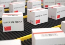 China’s Tech Titans Under Pentagon Spotlight Shipping boxes labeled made in China on a conveyor belt