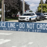 Police line barrier with parked police cars behind.