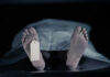 Feet with tag under white sheet in morgue