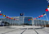 NATO headquarters with member flags in front under a clear blue sky