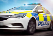 Police car driving with flashing lights visible