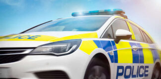 Police car driving with flashing lights visible