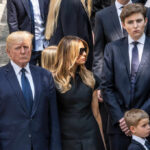 Three adults and a child in formal black attire standing on stone steps