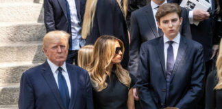Three adults and a child in formal black attire standing on stone steps