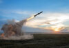 Rocket launching over a field at sunset