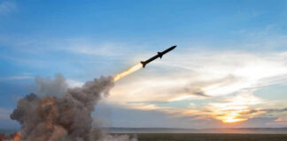 Rocket launching over a field at sunset