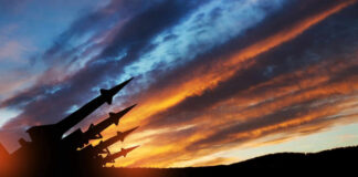 Silhouette of missiles against dramatic sunset sky.