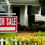 A 'For Sale' sign in front of a house