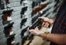 Why This Ruling Has Washington Nervous Person holding a handgun in a gun shop with various firearms displayed on the wall