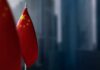 Journalist Tied To China? DOJ Drops Bomb Close-up of the Chinese flag on a flagpole with a blurred urban background