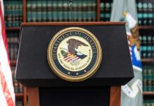 Iran Smuggling Ring Exposed — Sailors at Risk Podium with the Department of Justice seal and American flag in the background