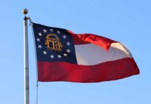 Big Money Steamrolls MAGA Favorite Georgia state flag waving against a clear blue sky