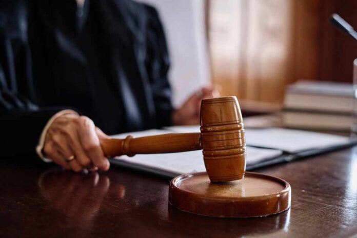 A judge's hand holding a gavel in a courtroom setting