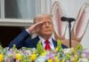 July Fourth Event Draws Political Criticism A man in a suit saluting in front of a floral display during an Easter event