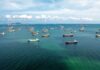 U.S. Threatens ‘Obliterate’ Response Aerial view of numerous cargo ships anchored in a blue ocean