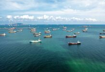 U.S. Threatens ‘Obliterate’ Response Aerial view of numerous cargo ships anchored in a blue ocean