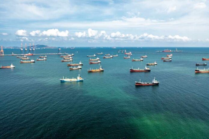Aerial,View,Of,Numerous,Oil,And,Gas,Tankers,Anchored,In Aerial view of numerous cargo ships anchored in a blue ocean