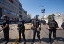 Active Shooter Traps City In Chaos Police officers in riot gear standing on a street during a protest