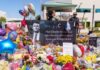 Memorial with flowers, balloons, flags, and a large tribute poster