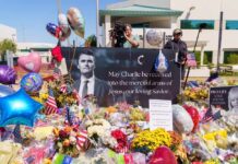Memorial with flowers, balloons, flags, and a large tribute poster