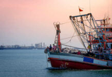 Trump Unlocks Massive Pacific Fishing Grounds Fishing boat on the water during sunset with an industrial area in the background