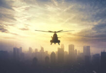 Mystery Crash Near Hormuz Stirs Nerves Silhouette of a helicopter flying over a city skyline at sunset