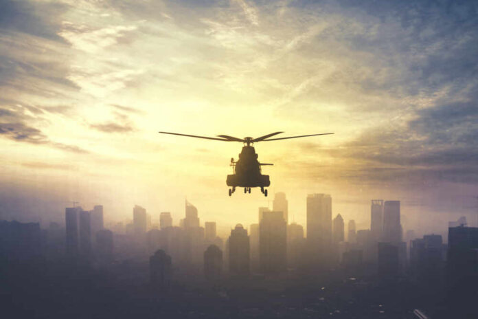 Silhouette,Of,Military,Helicopter,Hovering,Over,Downtown,,Shot,At,Sunset Silhouette of a helicopter flying over a city skyline at sunset