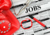 America’s Labor Market Is Cooling Job classifieds with phone, pen, and glasses.