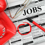 America’s Labor Market Is Cooling Job classifieds with phone, pen, and glasses.