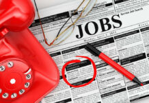 America’s Labor Market Is Cooling Job classifieds with phone, pen, and glasses.