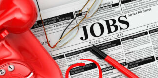 Job classifieds with phone, pen, and glasses.