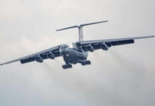 Large airplane flying in cloudy sky, frontal view.