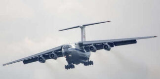Large airplane flying in cloudy sky, frontal view.