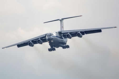 358411715 Large airplane flying in cloudy sky, frontal view.