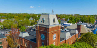 Clock tower surrounded by trees and buildings daytime