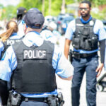 Police officers in vests walking through a crowded street