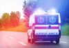 Key Epstein Figure Dies Amid Investigation Ambulance van with flashing lights on a rural road