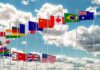 Row of international flags on tall poles against a cloudy sky