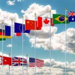 Trade War Deepens Between China And Europe Row of international flags on tall poles against a cloudy sky