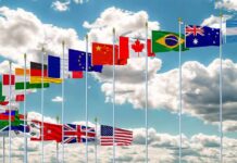 Row of international flags on tall poles against a cloudy sky