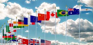 Row of international flags on tall poles against a cloudy sky