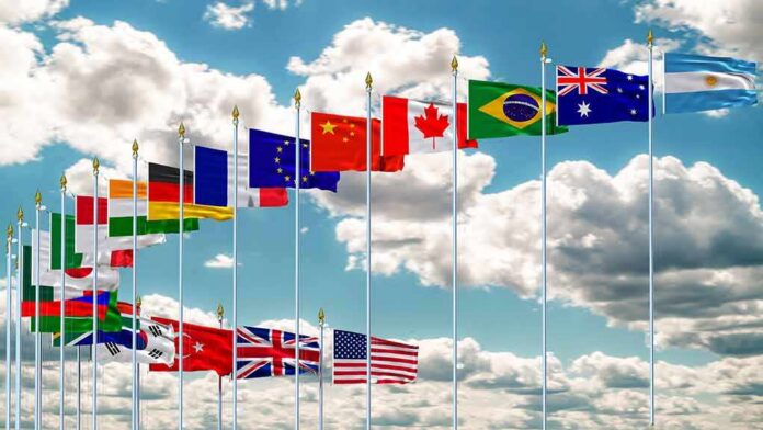 shutterstock_1146679565 Row of international flags on tall poles against a cloudy sky