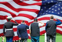 Veterans Call Shutdowns Dangerous For America Veterans salute a large American flag