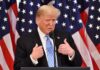 Who Keeps Targeting President Trump? man in suit speaking at podium with US flags behind