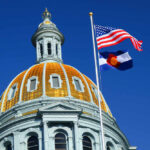 Grassroots Candidate Topples Democratic Giant The dome of a state capitol building with flags flying against a blue sky