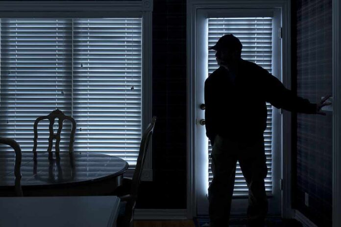 Silhouetted person in a dark room near a door with blinds